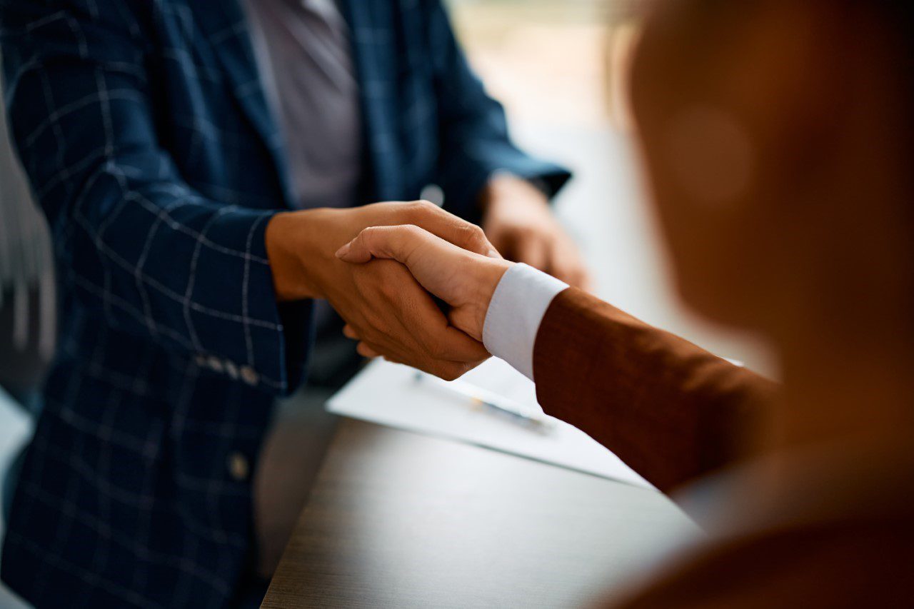 Close up of coworkers handshaking while greeting during business meeting in the office.